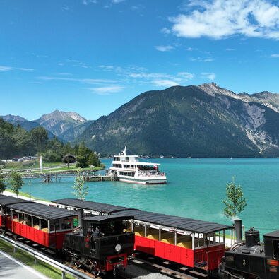 Bahn und Schiff am Achensee Die Luftaufnahme zeigt ein Schiff der Achenseeschifffahrt sowie die Achenseebahn an der Anlegestelle Seespitz im Sommer.