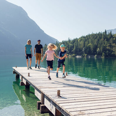 A family taking a break on a wooden pier during their hike on the Gaisalmsteig, enjoying the beautiful surroundings.