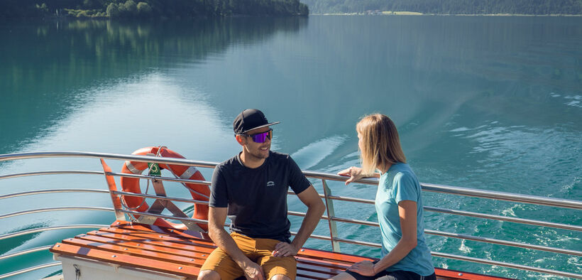 Ein Ausflug mit der Achenseeschifffahrt  Ein Pärchen begibt sich auf einen Ausflug mit der Achenseeschifffahrt, um gemeinsam das Wasser und die malerische Landschaft in vollen Zügen zu genießen.
