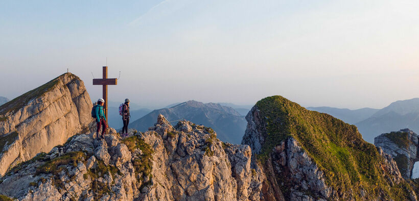 Zwei bergsportbegeisterte Frauen genießen die Morgenstimmung am Klettersteig Rosskopf im Rofangebirge.