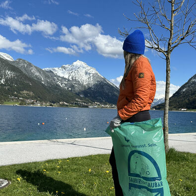 Eine junge Frau sammelt Müll an der Seeuferpromenade in Pertisau.