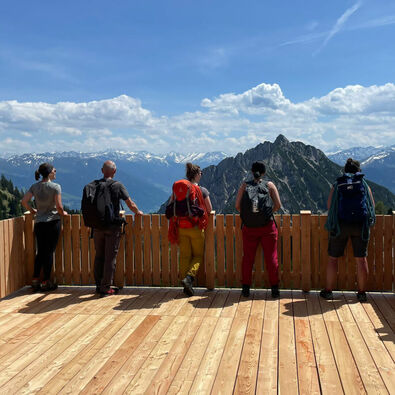 Klettern am Achensee Eine kleine Gruppe die gerade die Aussicht auf eine schöne Berglandschaft von einem Holzbalkon genießt.