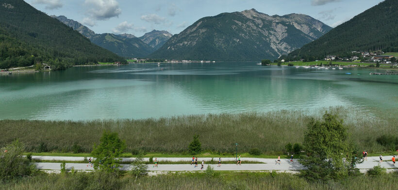 Achenseelauf 2023 Teilnehmer laufen auf der Achenseelauf-Strecke mit Blick auf den See.