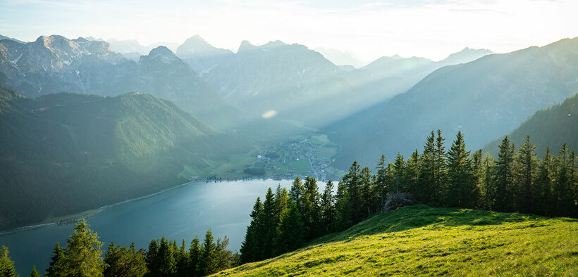 Die wiesenbedeckte Naturlandschaft des Rofangebirges mit Blick auf das Dörfchen Pertisau am Achensee.