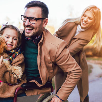 Barrierefreier Familienurlaub am Achensee Eine lachende Familie aus einem Rollstuhlfahrer, seiner Frau, Tochter und Hund im Sommer.