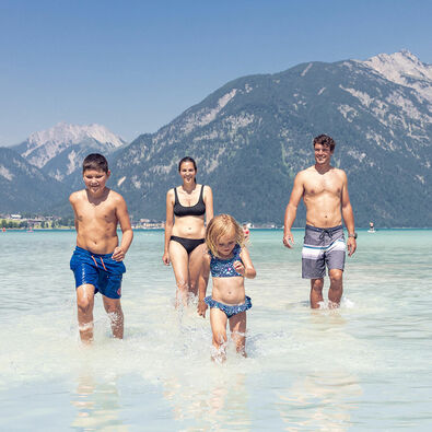 Badespaß mit der Familie in Maurach am Achensee Eine Familie genießt das schöne Wetter und badet im türkisblauen Achensee in Maurach.