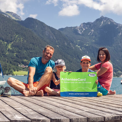 AchenseeCard Eine Familie am Steg in Pertisau am Achensee mit der AchenseeCard in der Hand.
