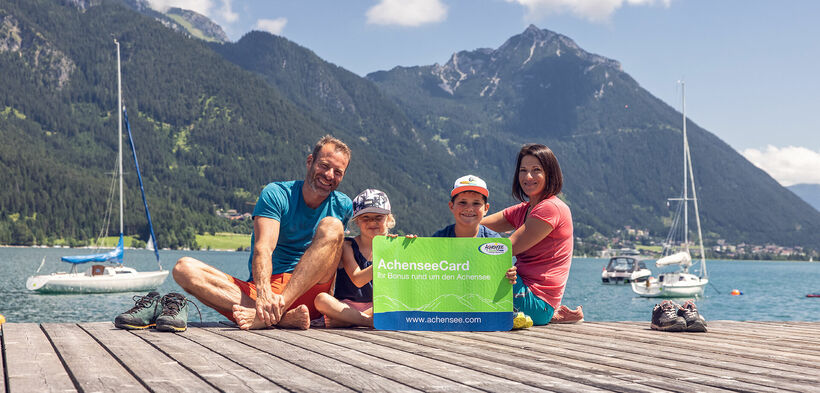 Eine Familie am Steg in Pertisau am Achensee mit der AchenseeCard in der Hand. 