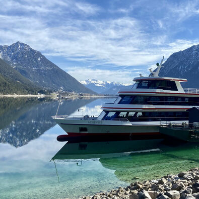 Die Achenseeschifffahrt in Pertisau am Achensee Die Achenseeschifffahrt legt hier in Pertisau am Achensee an. Im Hintergrund sind angezuckerte Berge wie das Ebner Joch zu sehen.